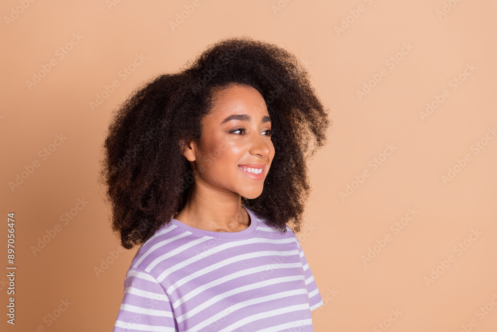 Photo of nice young woman curly hairstyle wear striped t-shirt isolated on beige color background Photo of nice young woman curly hairstyle wear striped t-shirt isolated on beige color background