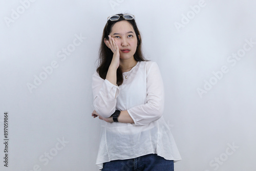 Annoyed reluctant asian woman standing bored and disappointed, lean on palm and looking up irritated, white background. Lifestyle, people emotions and casual concept