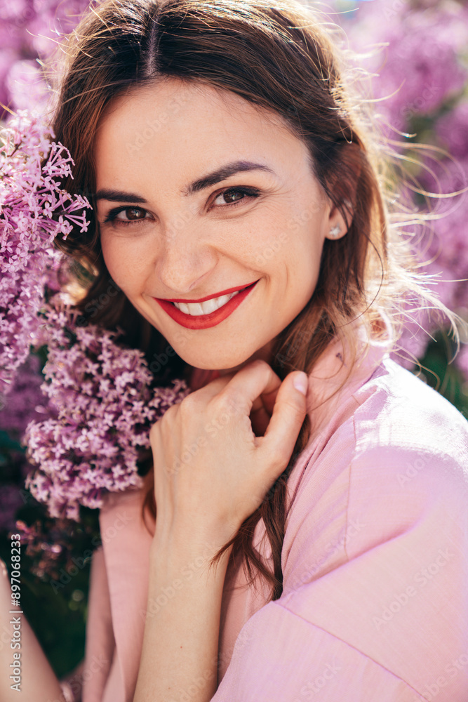 Young beautiful smiling woman. Sexy carefree model posing in the street. Positive model near blooming flower lilac bush beaming. Summertime, pink colours. Closeup beauty portrait, red lips Young beautiful smiling woman. Sexy carefree model posing in the street. Positive model near blooming flower lilac bush beaming. Summertime, pink colours. Closeup beauty portrait, red lips