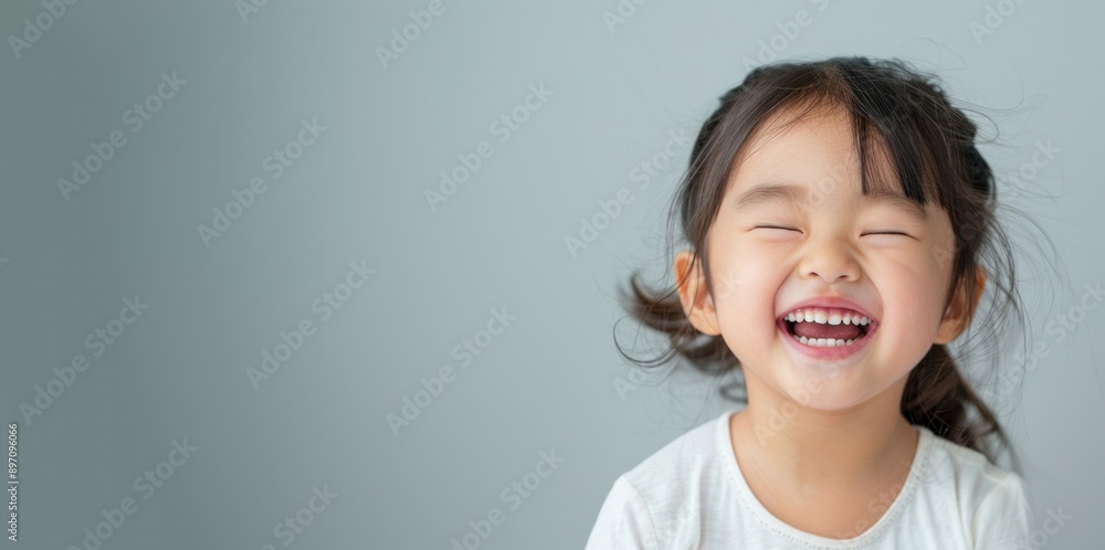 Portrait of a Little asian girl standing on light grey background, laughing out loud. Portrait of a Little asian girl standing on light grey background, laughing out loud.