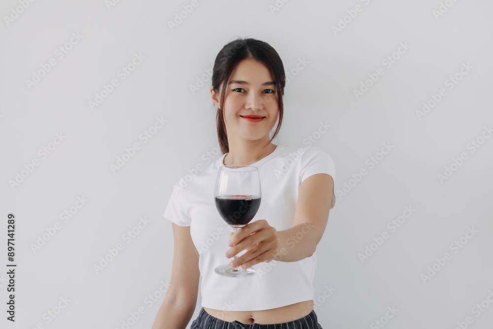 Asian Thai woman holding, offering and showing a glass of red wine, happy smiling drinking while standing isolated over white background wall. Asian Thai woman holding, offering and showing a glass of red wine, happy smiling drinking while standing isolated over white background wall.