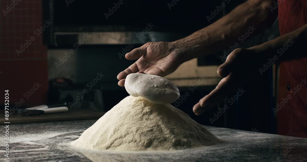 Super slow motion of professional artisan baker chef kneads dough with flour while making homemade bread, pasta or pizza on rustic wooden table in traditional bakery kitchen.