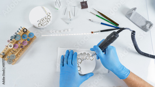 dental technician processes a zircon tablet with milled crowns, on a table with different tools