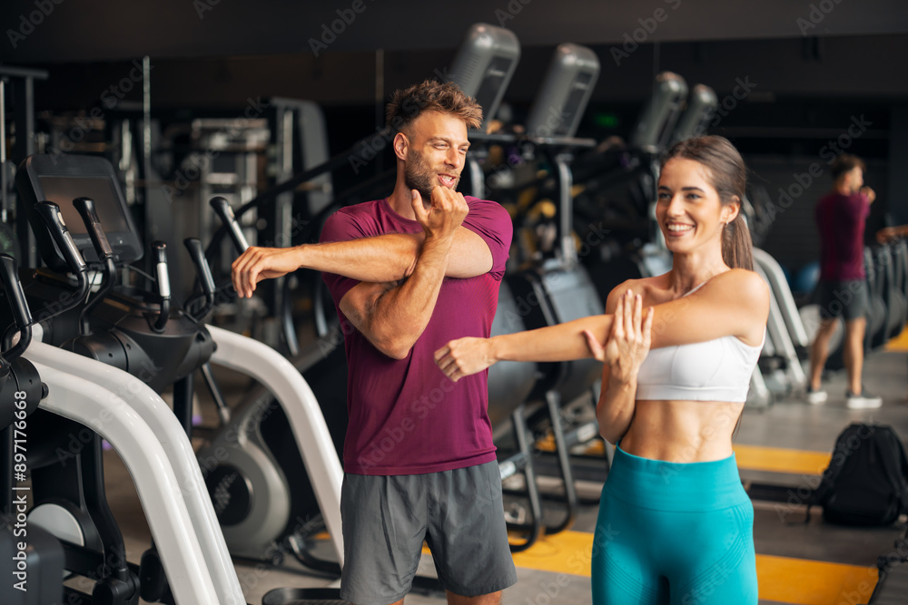 A fit young adult couple doing stretching exercises together at the gym A fit young adult couple doing stretching exercises together at the gym