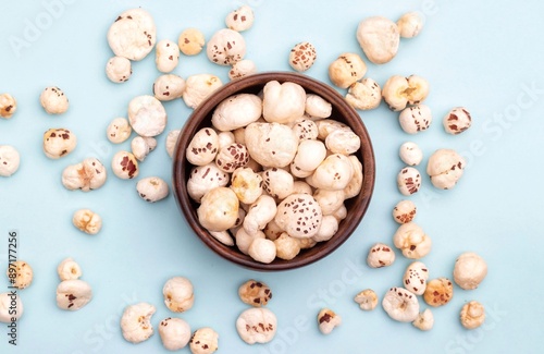 Top View of Makhana or Fox Nut in a Wooden Bowl Isolated on Light Blue Background with Copy Space, Also Known as Lotus Seed Pop, Euryale Ferox or Gorgon Nut