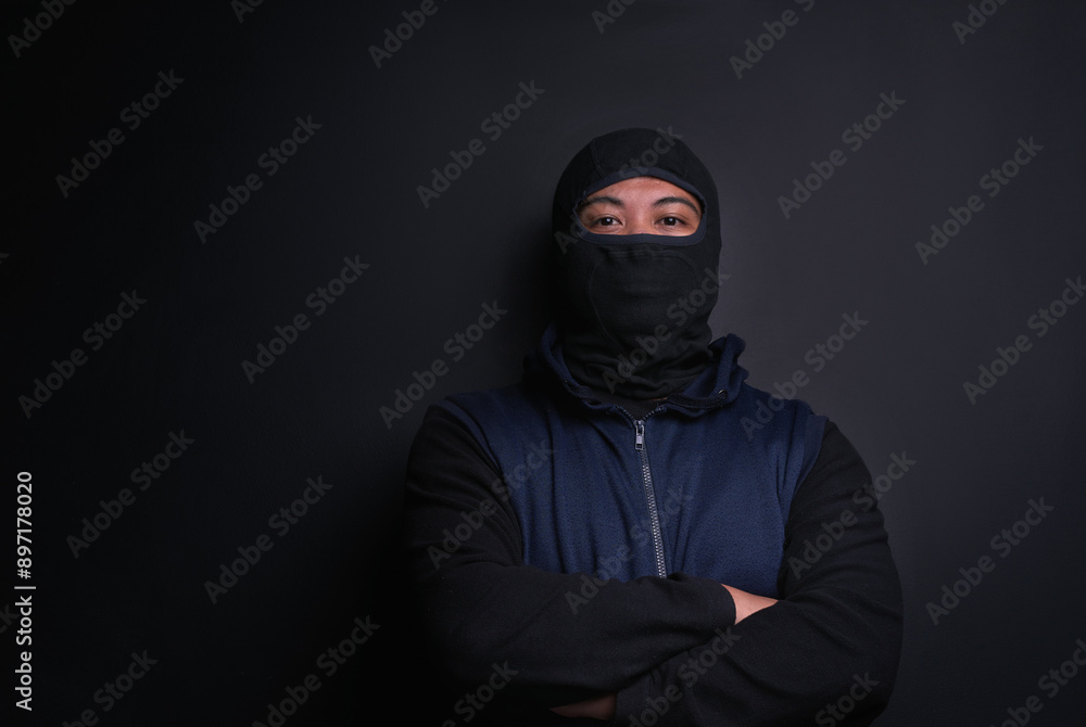 Man, portrait and mask of robber in studio, burglar and criminal or black background for thief. Male person, balaclava and disguise for bad guy on mockup space, danger and gangster for illegal action Man, portrait and mask of robber in studio, burglar and criminal or black background for thief. Male person, balaclava and disguise for bad guy on mockup space, danger and gangster for illegal action