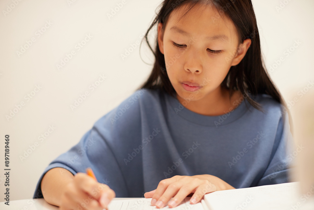 夏休みの小学生の女の子が家で宿題をする姿