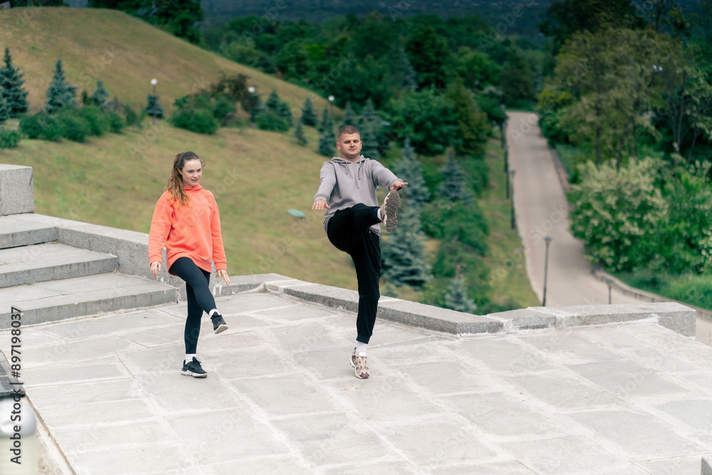 Fototapeta premium in the park a young couple in love doing sports couples warming up healthy lifestyle synchronized movements