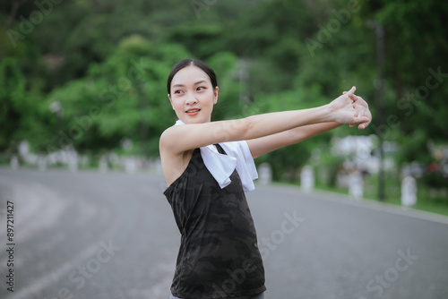 A young, beautiful Asian woman runs happily in a city park on a summer morning. Embracing an active lifestyle, she enjoys outdoor exercise, showcasing fitness, health, vitality, and a joyful, healthy 