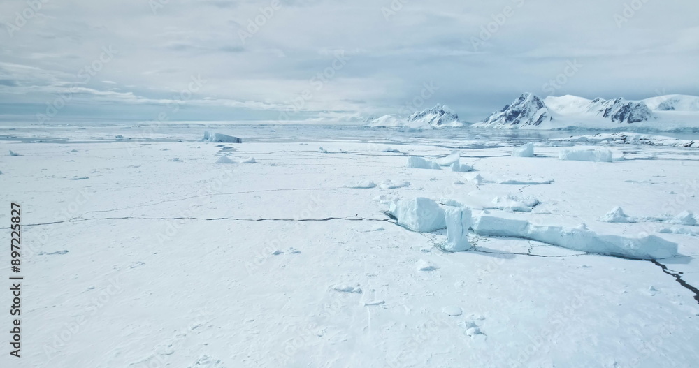 Desert white land of snow and ice, frozen polar ocean coast landscape. Icebergs stuck in snow covered sea cracked ice. South Pole winter wild nature. Antarctica travel, exploration. Aerial panorama Desert white land of snow and ice, frozen polar ocean coast landscape. Icebergs stuck in snow covered sea cracked ice. South Pole winter wild nature. Antarctica travel, exploration. Aerial panorama
