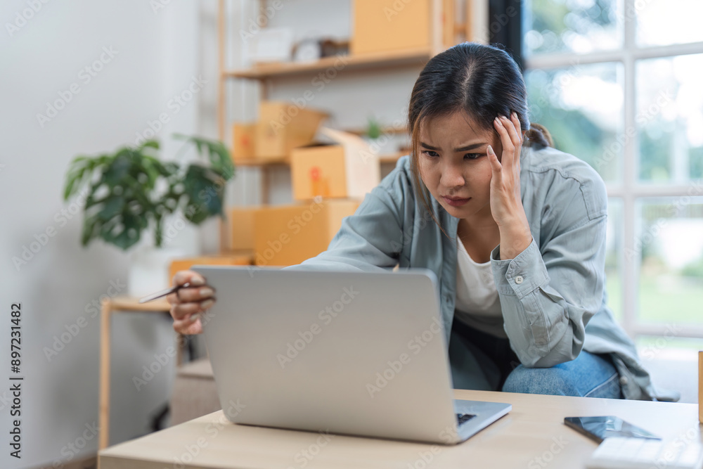 Stressed Young Woman Selling Items Online from Home, Experiencing Frustration and Anxiety While Managing Online Sales Stressed Young Woman Selling Items Online from Home, Experiencing Frustration and Anxiety While Managing Online Sales