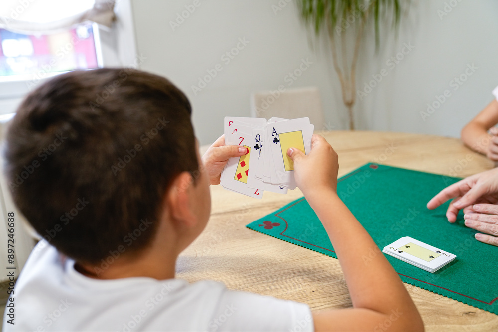 Naklejka premium A young boy is playing a card game with his family