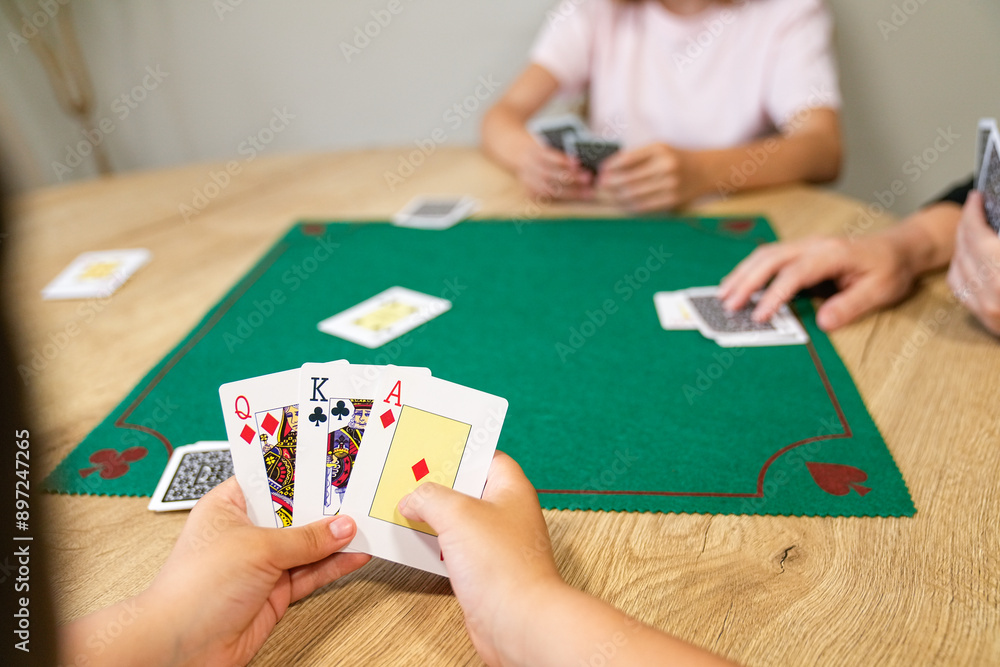 Obraz premium A child is holding a deck of cards and playing a game with other children