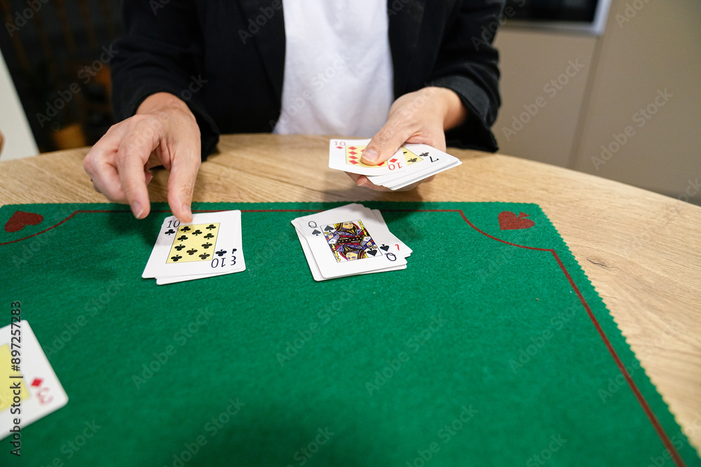 A person is playing a card game with a deck of cards on a green table A person is playing a card game with a deck of cards on a green table