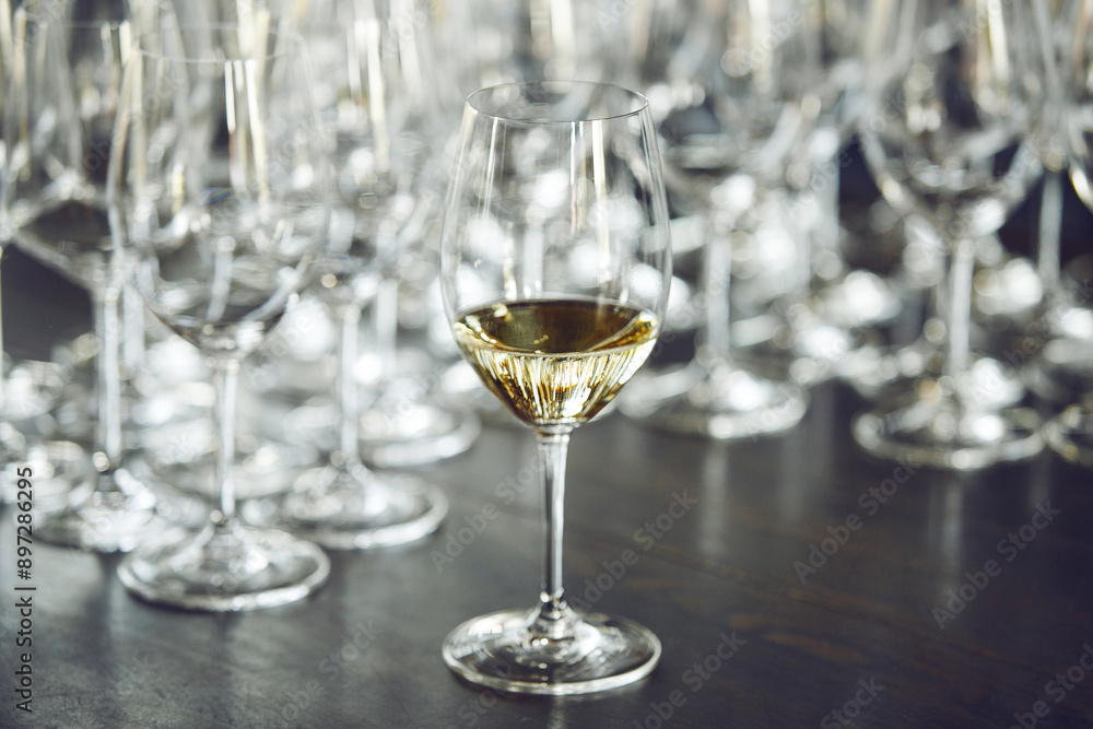 Glas of white wine on table against empty bokals background. Alcholic beverages tasting. Glas of white wine on table against empty bokals background. Alcholic beverages tasting.