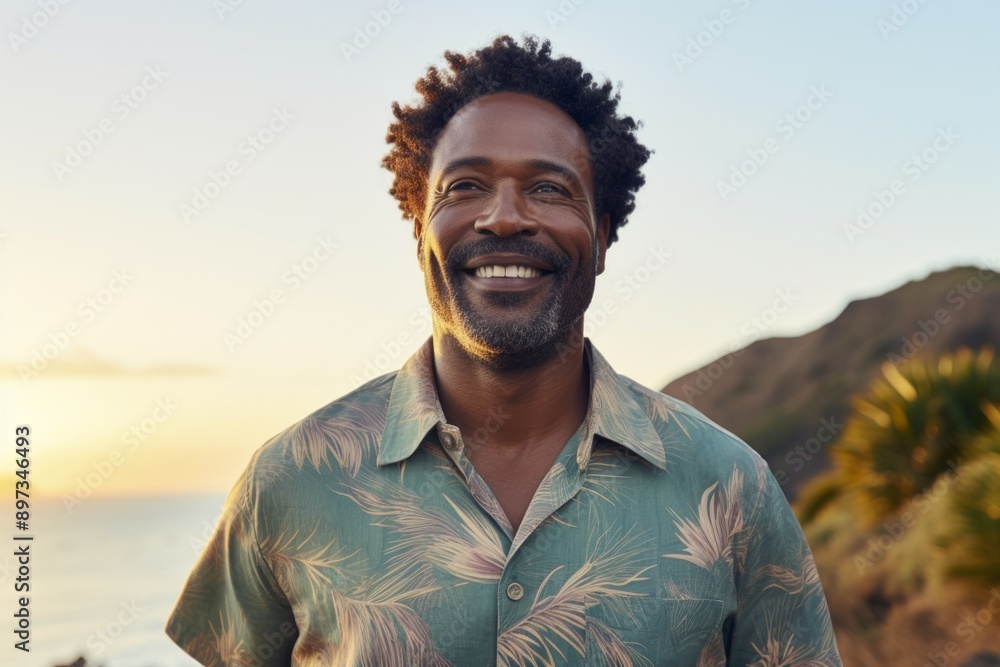 Portrait of a cheerful afro-american man in his 40s sporting a breathable hiking shirt isolated in beautiful beach sunset Portrait of a cheerful afro-american man in his 40s sporting a breathable hiking shirt isolated in beautiful beach sunset