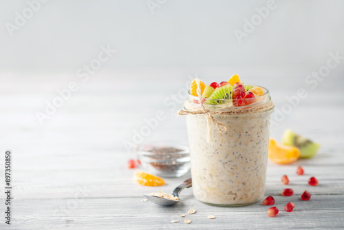 Healthy diet breakfast. Overnight oatmeal with chia seeds and fruits in a glass jar on a wooden background. photo