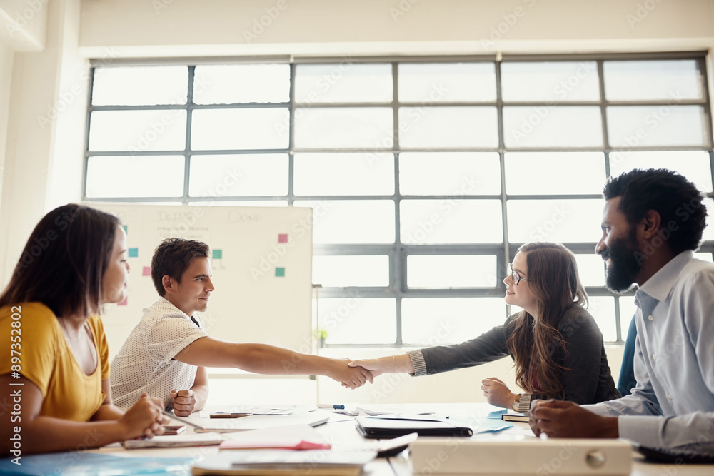 Fototapeta premium Business people, smile and handshake by desk for partnership, creative collaboration and success in office. Team meeting, happy and shaking hands for deal negotiation, b2b opportunity and thank you