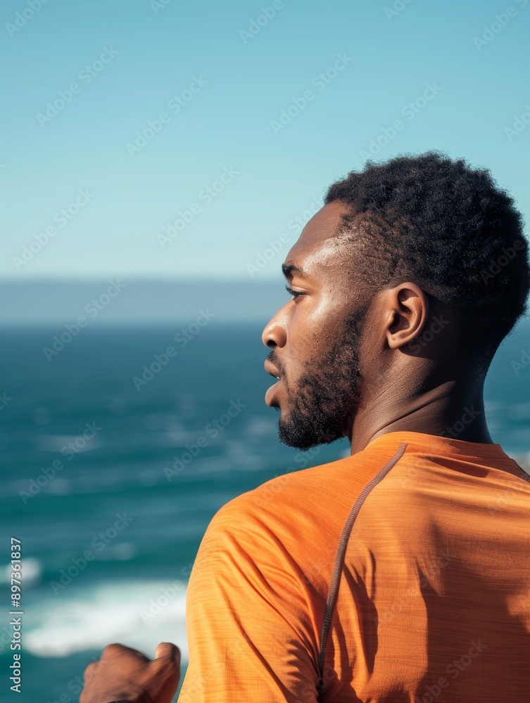 Man in orange shirt looks out at ocean on sunny day Man in orange shirt looks out at ocean on sunny day