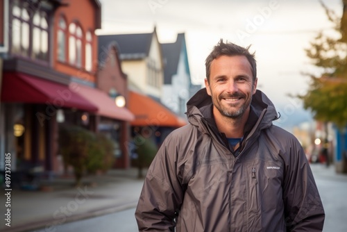 Portrait of a happy man in his 40s wearing a lightweight packable anorak on charming small town main street