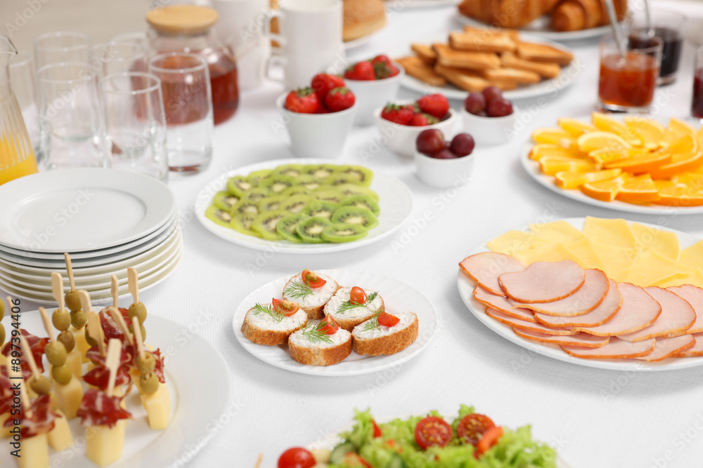 Different meals served on white table indoors. Buffet menu Different meals served on white table indoors. Buffet menu