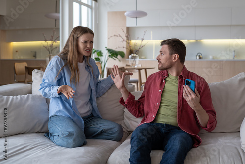 Fotografie Husband and wife arguing, gesturing wildly and shouting on sofa