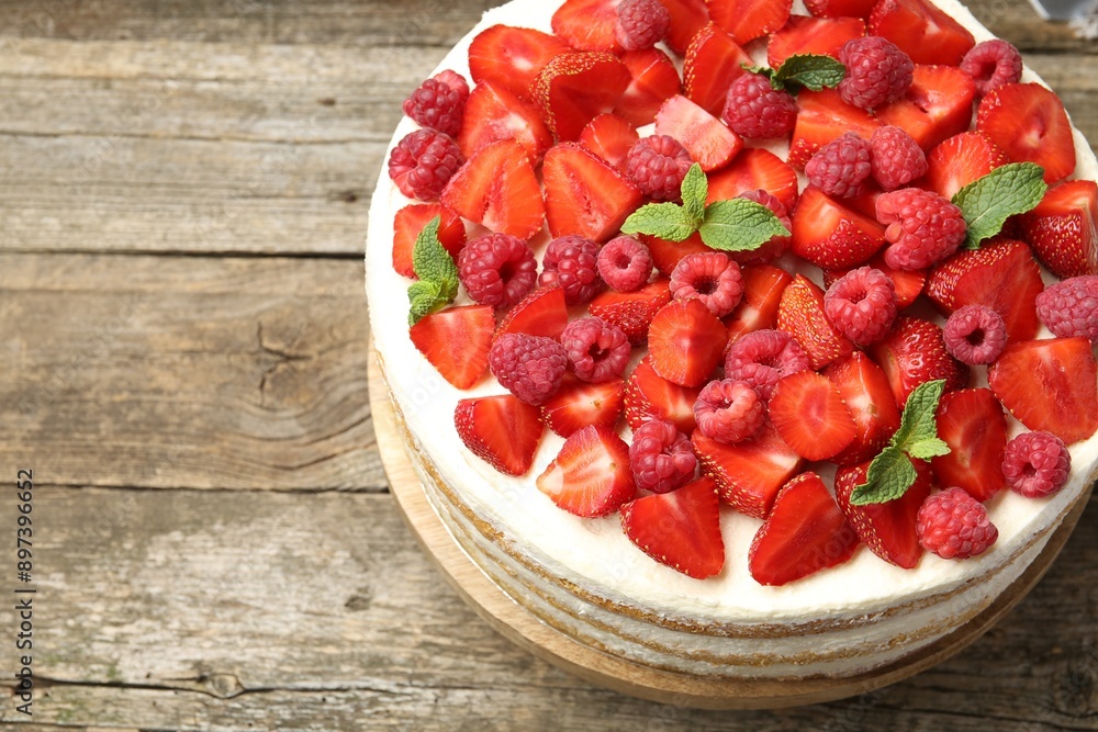 Tasty sponge cake with fresh berries and mint on wooden table, above view. Space for text Tasty sponge cake with fresh berries and mint on wooden table, above view. Space for text