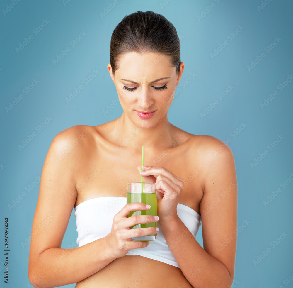 Woman, green smoothie and unhappy detox in studio, weight loss beverage and blue background. Female person, laugh and organic juice or raw shake for nutrition, vitamin and vegan supplement for health Woman, green smoothie and unhappy detox in studio, weight loss beverage and blue background. Female person, laugh and organic juice or raw shake for nutrition, vitamin and vegan supplement for health
