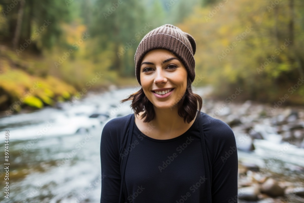 Portrait of a happy woman in her 30s sporting a trendy beanie in front of tranquil forest stream Portrait of a happy woman in her 30s sporting a trendy beanie in front of tranquil forest stream