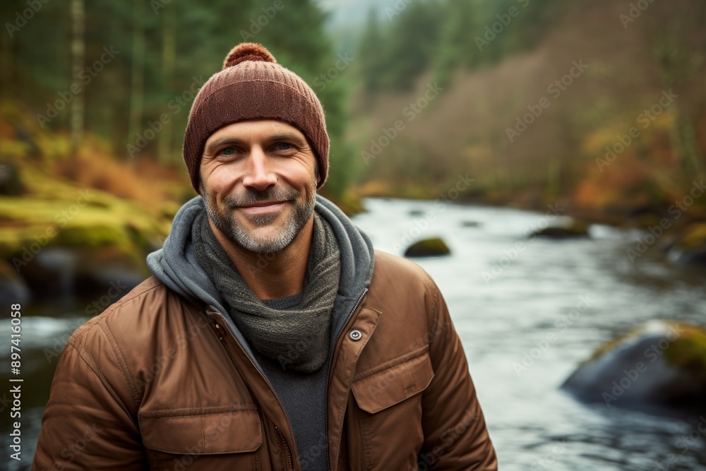 Portrait of a satisfied man in his 40s donning a warm wool beanie over tranquil forest stream Portrait of a satisfied man in his 40s donning a warm wool beanie over tranquil forest stream