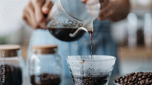 A barista skillfully pours freshly brewed coffee into a glass container, surrounded by coffee beans and related equipment, embodying artisanal coffee culture.