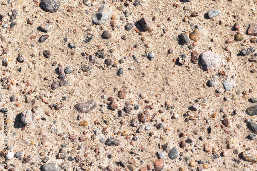 Small stones are in wet sand on the shore of the Baltic Sea, top view Small stones are in wet sand on the shore of the Baltic Sea, top view