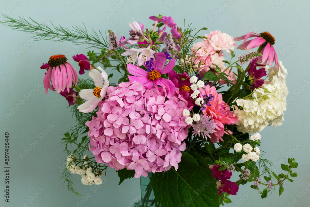 A bouquet of summer flowers in the room. Hydrangea, rose, echinacea, mint, snapdragon, asparagus and other flowers.