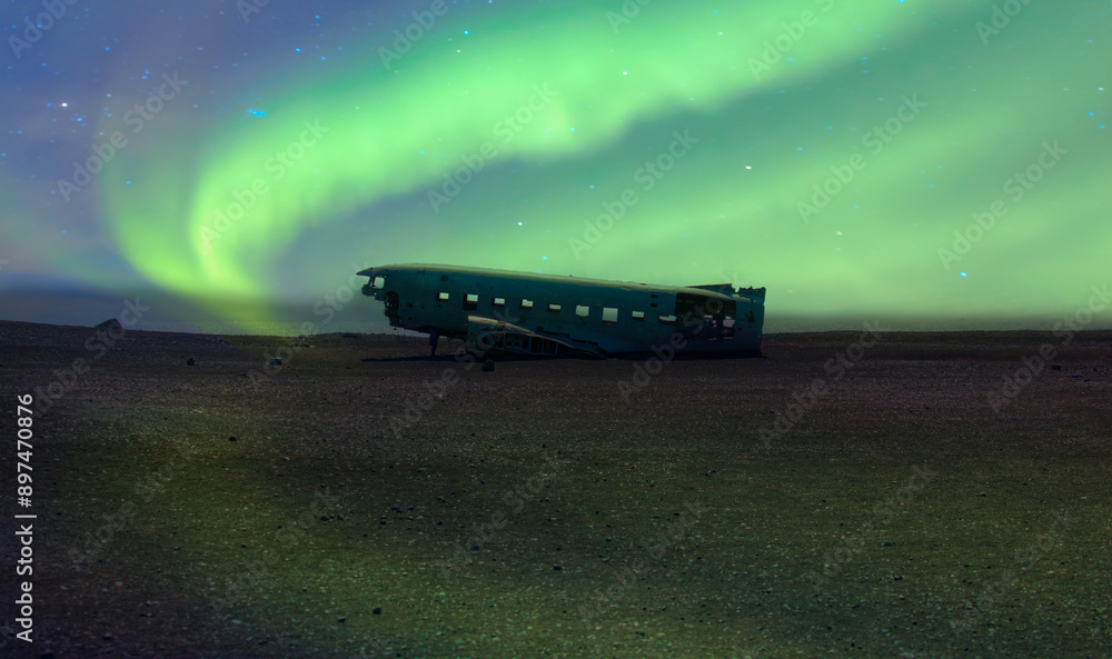 Obraz premium Scenic view of DC-3 airplane wreckage with aurora borealis at black beach Full moon in the background - Sólheimasandur, Iceland 