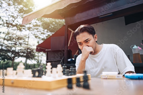A Southeast Asian man is confused while playing chess in the afternoon at a traditional coffee shop