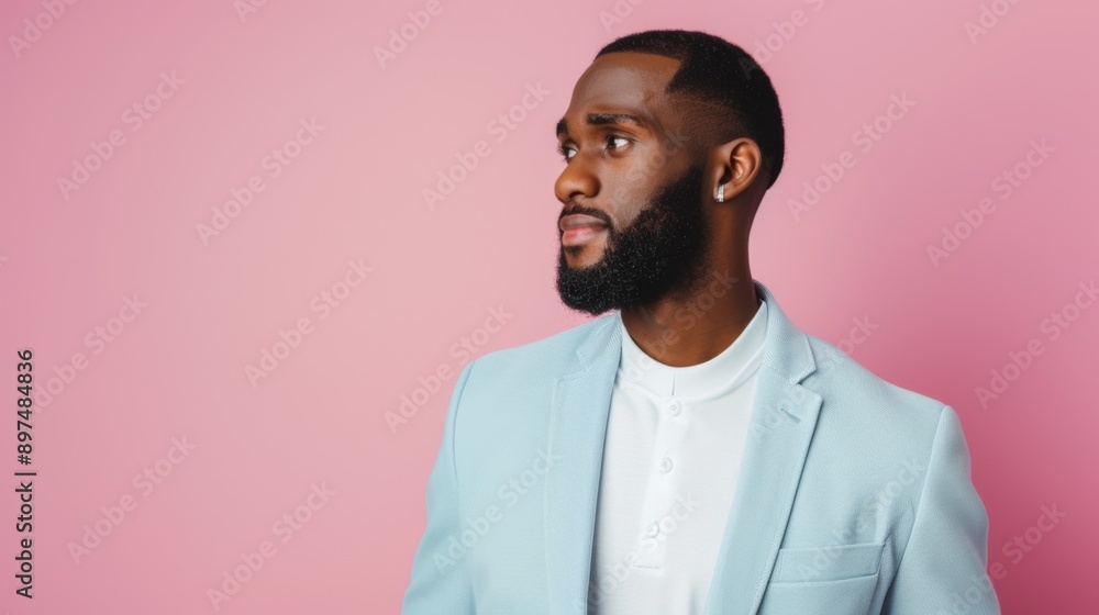 A man with a beard and a blue suit is standing in front of a pink wall A man with a beard and a blue suit is standing in front of a pink wall