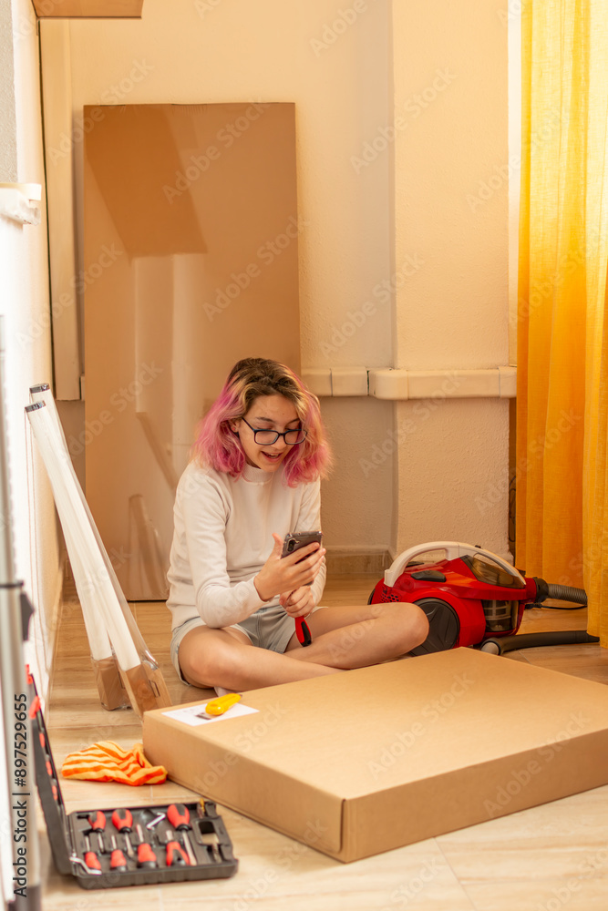 young girl with everything ready to assemble some furniture, talking on the cell phone young girl with everything ready to assemble some furniture, talking on the cell phone