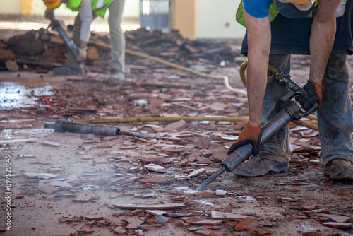 A construction worker on a renovation site using a pneumatic hammer, focused and skillful, breaking through concrete for a precise and efficient remodeling job.