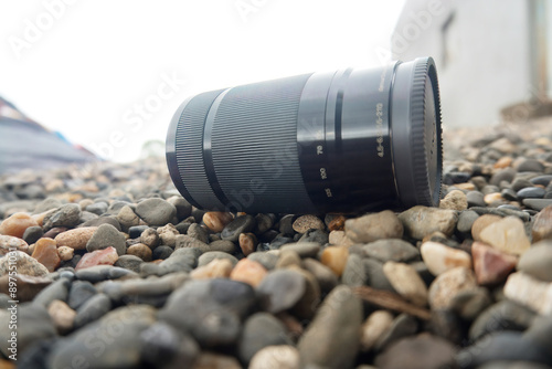 Abandoned Camera Lens on Pebble Ground - Photography Gear, Among the pebbles lies a camera lens, quietly waiting to capture the beauty of its surroundings.