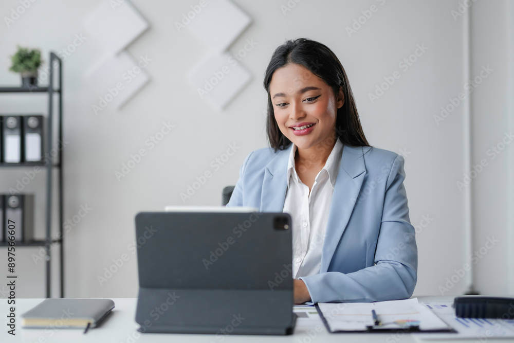 Asian businesswoman is smiling while working from her office on her digital tablet Asian businesswoman is smiling while working from her office on her digital tablet