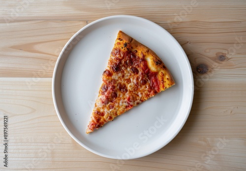 A slice of pizza on an all-white plate, placed in the center of a light wooden table