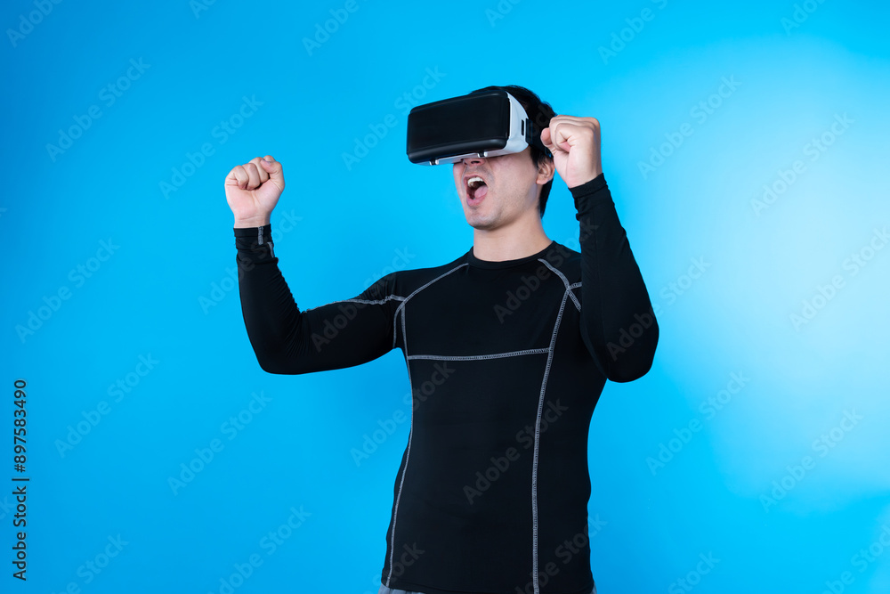Smart gaming player wearing VR glasses raising fist up isolated blue background screen connecting digital futuristic technology virtual reality at metaverse world playing hologram arena. Contrivance. Smart gaming player wearing VR glasses raising fist up isolated blue background screen connecting digital futuristic technology virtual reality at metaverse world playing hologram arena. Contrivance.