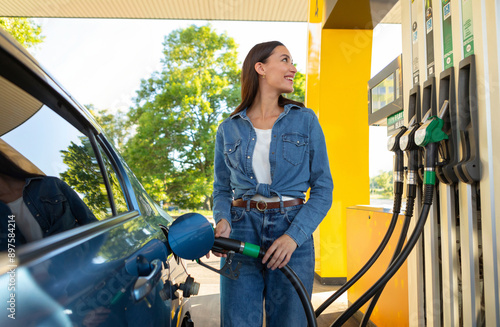 Cuadro en lienzo Happy woman refueling her car at petrol station, cheerful female driver standing