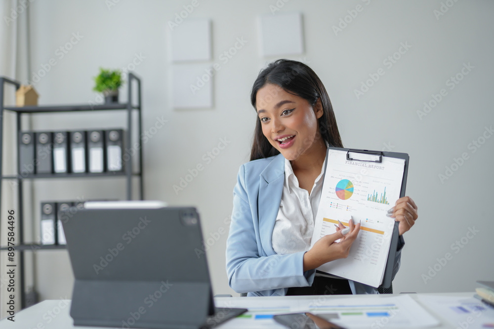 Businesswoman is holding a financial report with charts and graphs while having a video conference on a tablet Businesswoman is holding a financial report with charts and graphs while having a video conference on a tablet