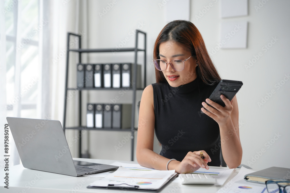 Asian accountant woman is working with calculator, laptop and documents at her office desk Asian accountant woman is working with calculator, laptop and documents at her office desk