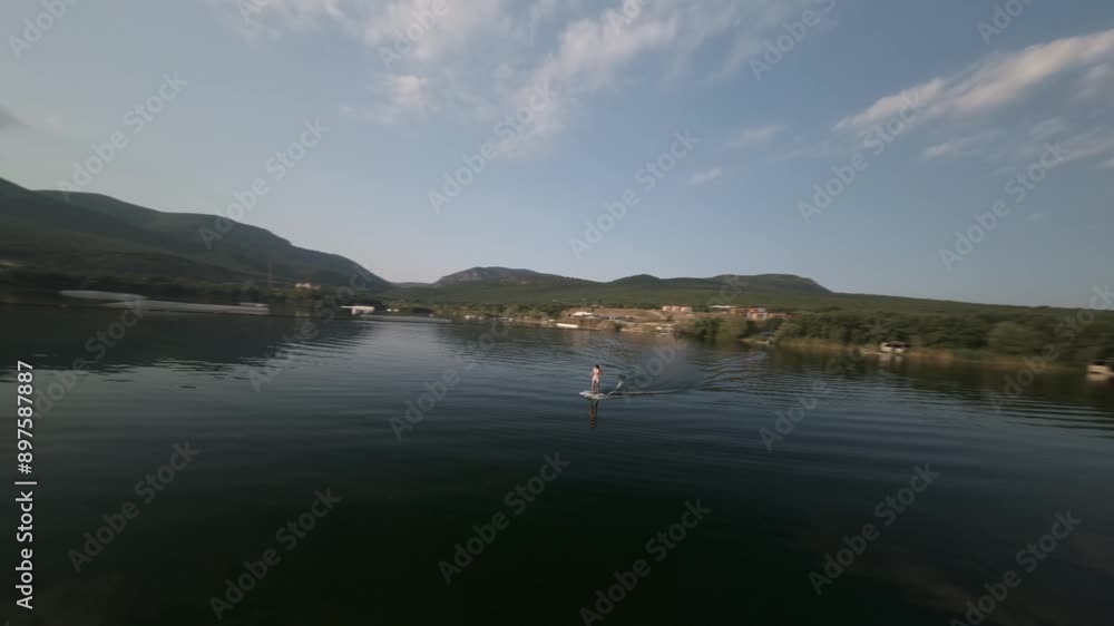 Girl rides hydrofoil beautifully on smooth water on lake early in the morning at dawn. High quality 4k footage fpv drone shot Girl rides hydrofoil beautifully on smooth water on lake early in the morning at dawn. High quality 4k footage fpv drone shot