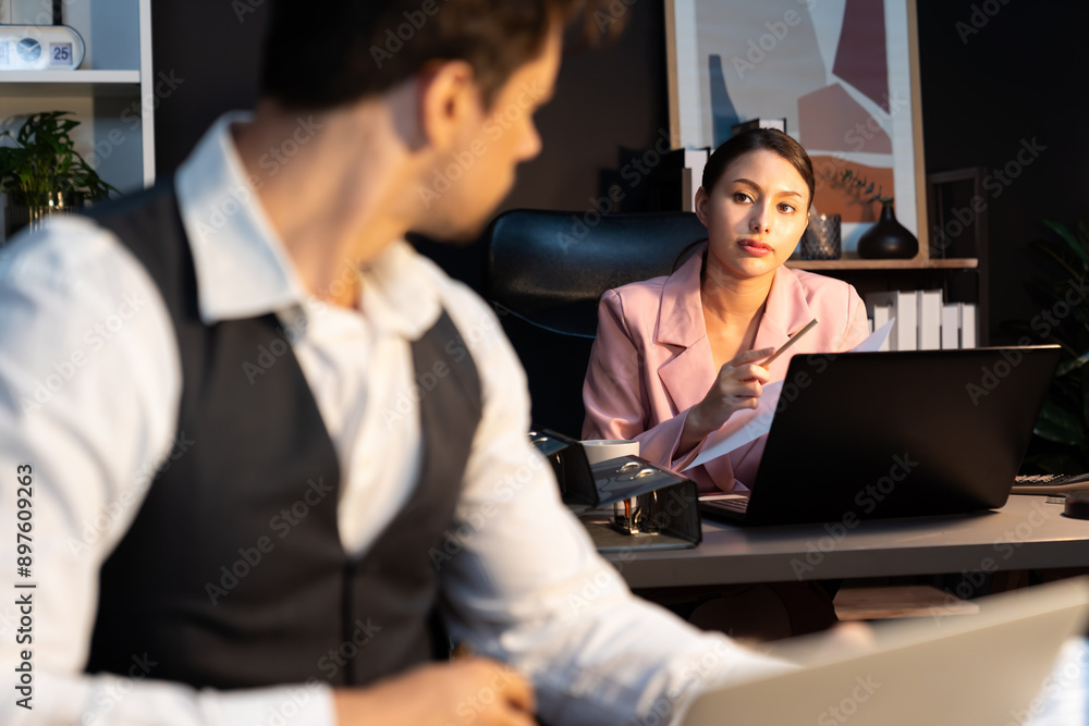 Focusing on sitting on pink suit woman presenting graph target on paperwork to explain customer market target graph report's business expansion to coworker while man holding paper to sign. Postulate. Focusing on sitting on pink suit woman presenting graph target on paperwork to explain customer market target graph report's business expansion to coworker while man holding paper to sign. Postulate.