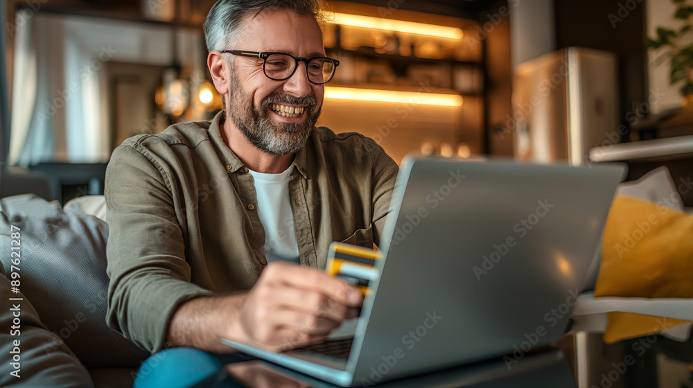 Smiling Mature Man Shopping Online With Credit Card And Laptop At Home Smiling Mature Man Shopping Online With Credit Card And Laptop At Home
