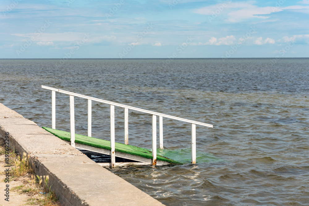 Wooden gangway into the sea at the beach on a sunny day Wooden gangway into the sea at the beach on a sunny day