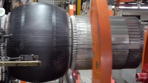 Robotic tire manufacturing machine stamping rubber tape in modern manufacture. Technological automotive industrial mechanism working at factory producing car tyre